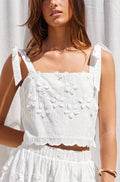 Woman wearing a white lace top against a white curtain background