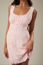 Woman wearing a pink patterned dress against a neutral background