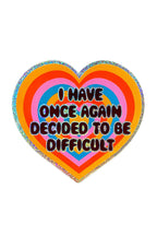 A colorful heart-shaped sticker with text 'I HAVE ONCE AGAIN DECIDED TO BE DIFFICULT' in the center.