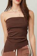 Woman wearing a brown strapless top and pants with white stripes on a plain background