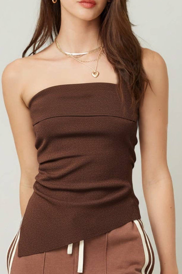 Woman wearing a brown strapless top and pants with white stripes on a plain background