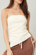 Woman wearing a white strapless top and brown pants with a white background