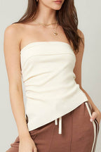 Woman wearing a white strapless top and brown pants with a white background