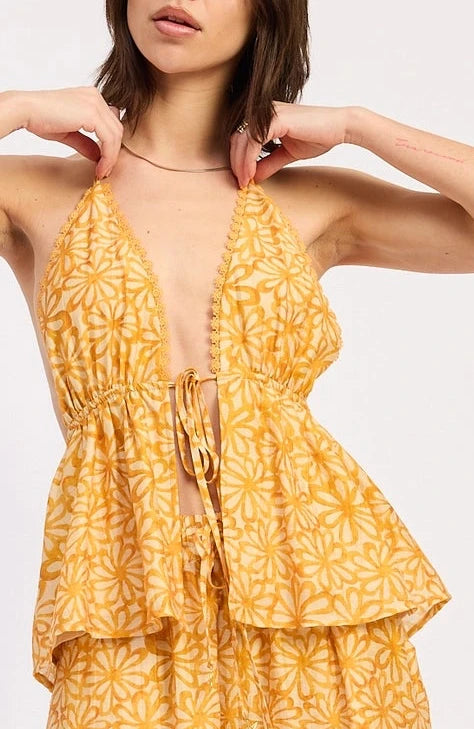 Woman wearing a yellow floral halter top on a white background