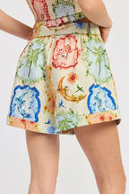 Woman wearing a colorful floral and moon-themed romper on a white background