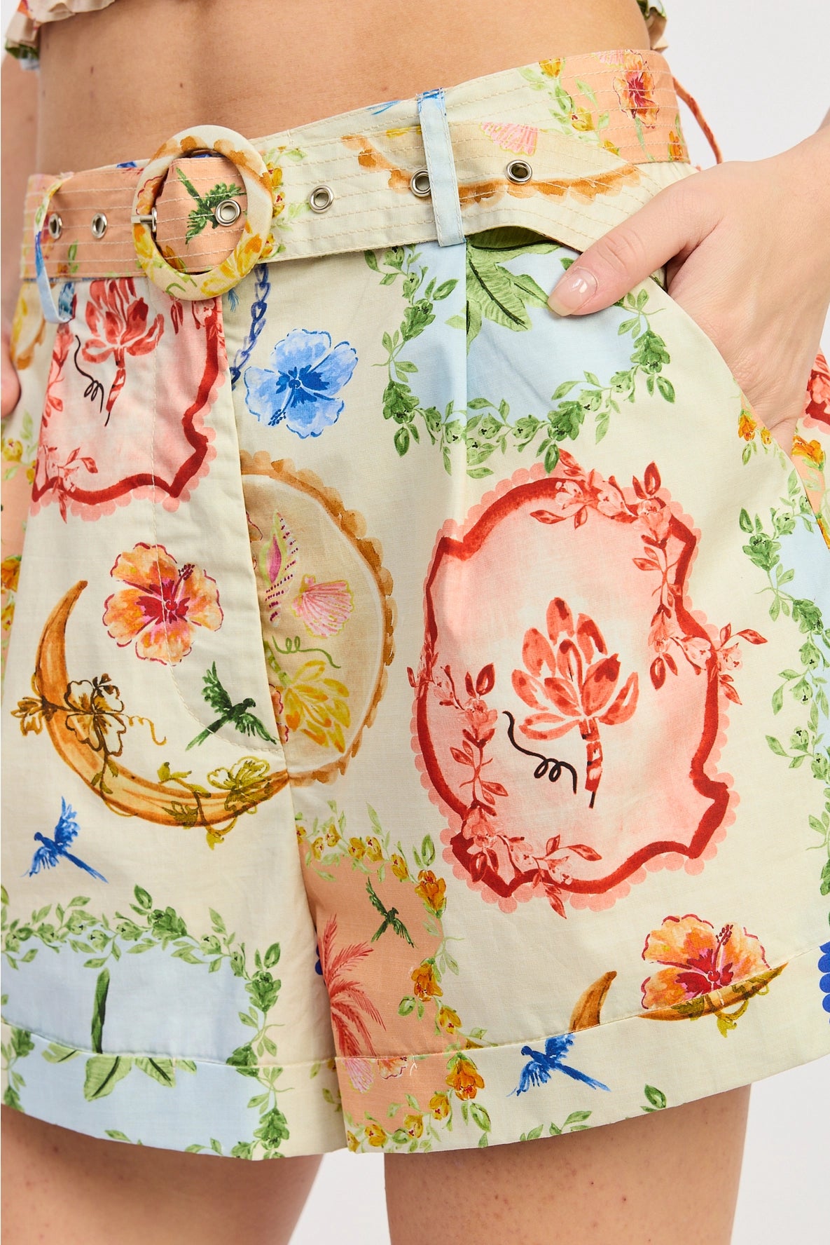 Colorful floral shorts with a belt worn by a person on a white background