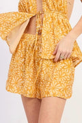 Woman wearing a yellow floral short with white sneakers on a white background