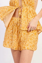 Woman wearing a yellow floral short with white sneakers on a white background
