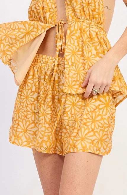 Woman wearing a yellow floral short with white sneakers on a white background