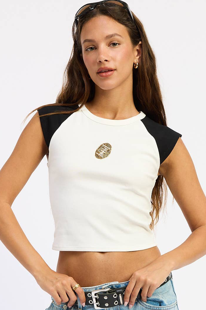 Woman wearing a white and black crop top and light blue jeans on a white background