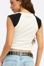 Woman wearing a black and white sleeveless top with blue jeans on a light gray background
