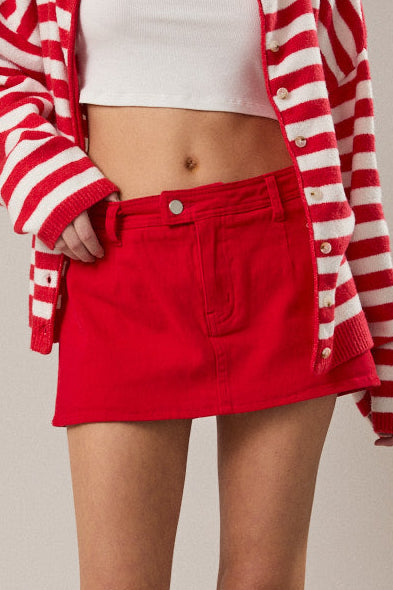 Woman wearing a red and white striped cardigan, white top, and red skirt on a beige background