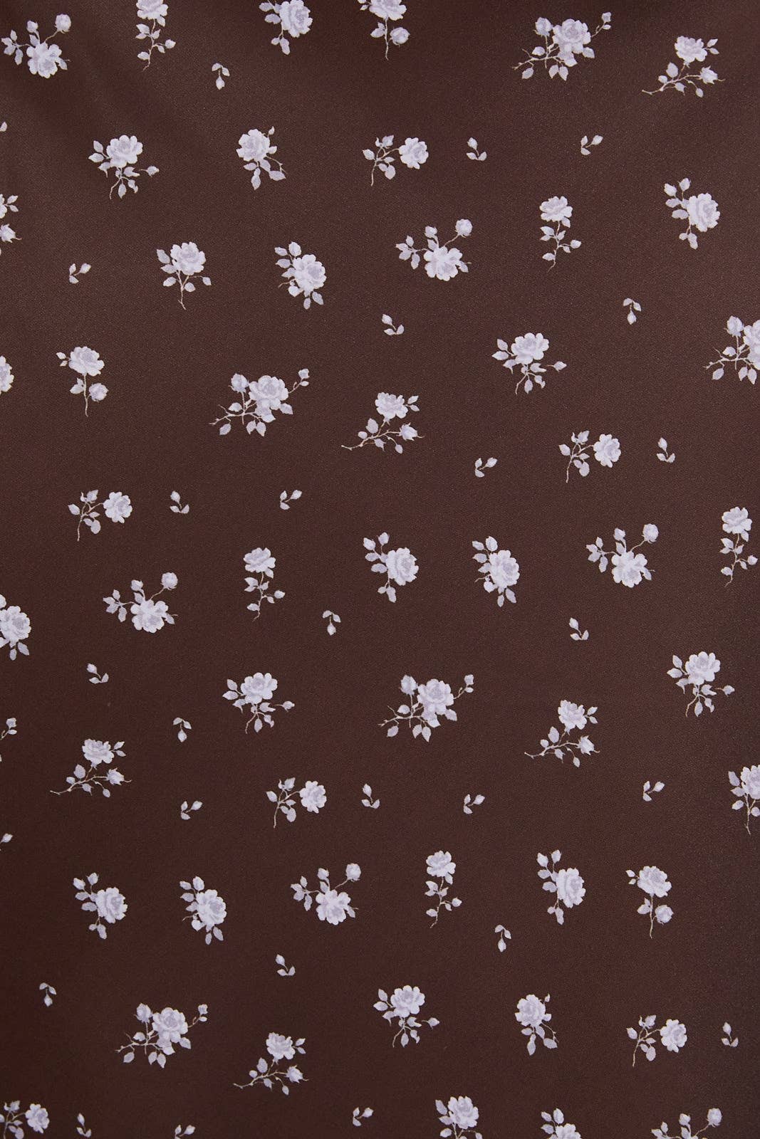 A close-up of a dark brown fabric with a repeating pattern of small white and light pink floral motifs.
