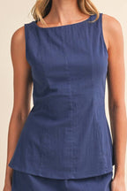 Woman wearing a blue sleeveless top and skirt set on a beige background