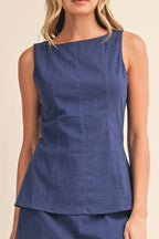 Woman wearing a blue sleeveless top and skirt set on a beige background