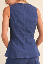 Woman wearing a blue sleeveless top and shorts set on a beige background