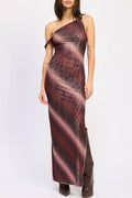 A woman modeling a one-shoulder mesh maxi dress with a dark red and black abstract pattern, paired with dark brown boots, against a plain white studio background.