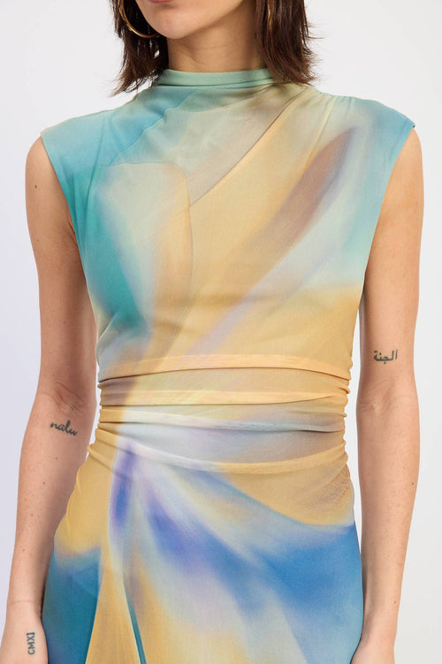 Woman wearing a sleeveless dress with a gradient of blue, green, and yellow on a white background.