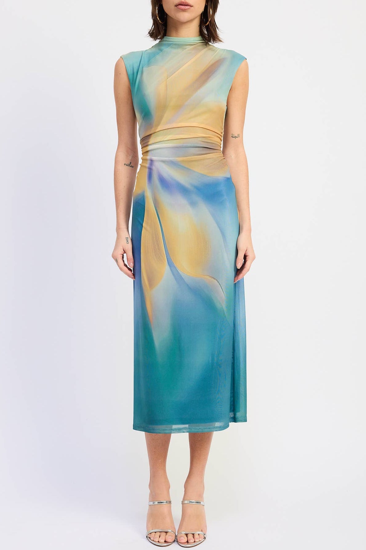 Woman wearing a sleeveless dress with a colorful abstract pattern on a white background