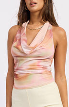 Woman wearing a sleeveless tie-dye top and light-colored shorts on a white background