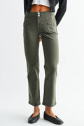 A woman modeling a pair of olive green cropped straight-leg jeans, styled with a black cardigan, white crop top, and black flats, against a light gray studio background.