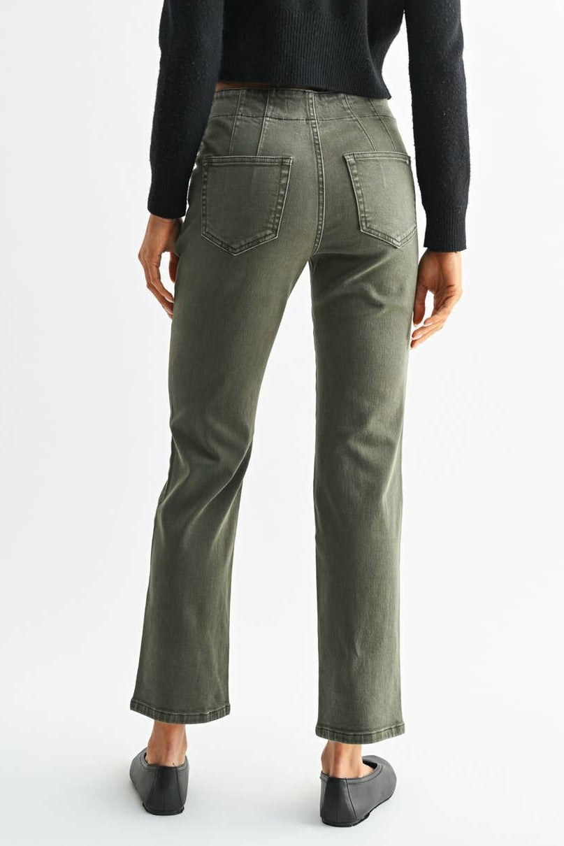 A woman shown from the back wearing a black long-sleeve cropped top and olive green straight-leg jeans, paired with black flats, against a plain white studio background.