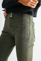 Close-up of a person wearing olive green high-waisted jeans with a black ribbed sweater, showing the front pocket and waistband details.