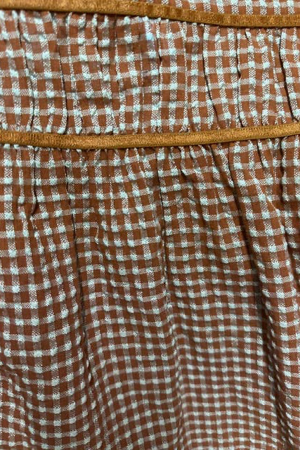 Close-up of a brown and white gingham patterned fabric with a tan elastic waistband.