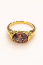 Gold ring with a brown gemstone on a white background