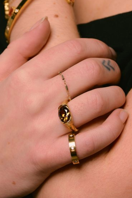 Close-up of a hand wearing gold rings with a blurred background