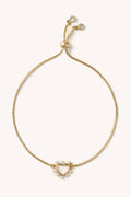 Gold bracelet with heart-shaped clasp on a white background
