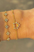 Gold bracelet with floral designs on a wrist against a blurred background