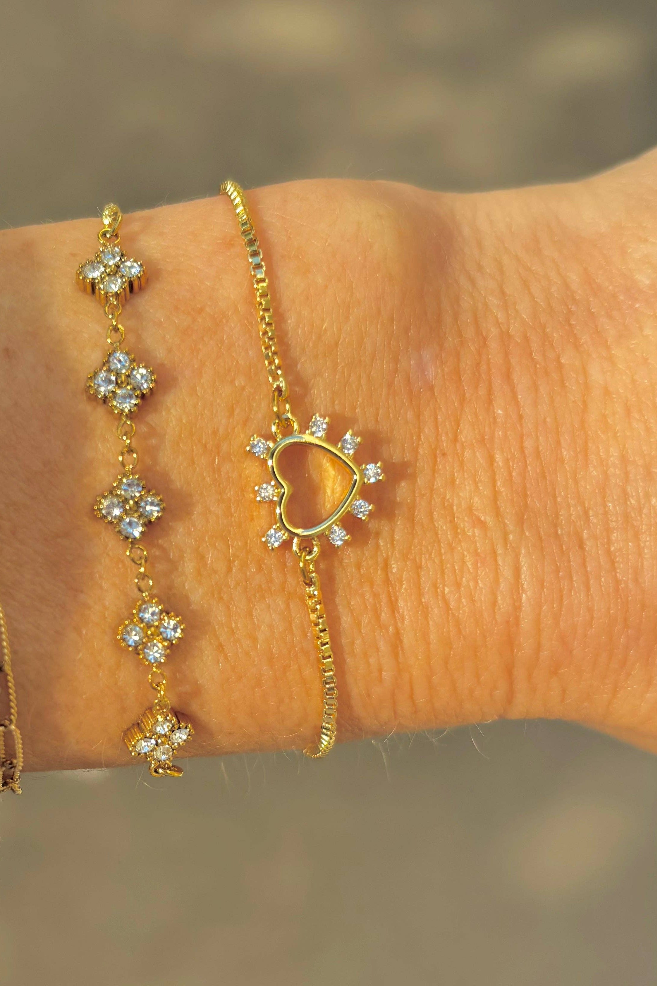 Gold bracelet with floral designs on a wrist against a blurred background