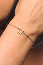 Close-up of a person wearing a gold bracelet with a heart charm.
