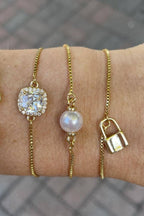 Four gold bracelets with different designs on a wrist against a blurred background