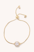 Gold bracelet with a clear gemstone on a white background