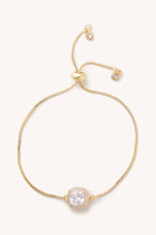 Gold bracelet with a clear gemstone on a white background