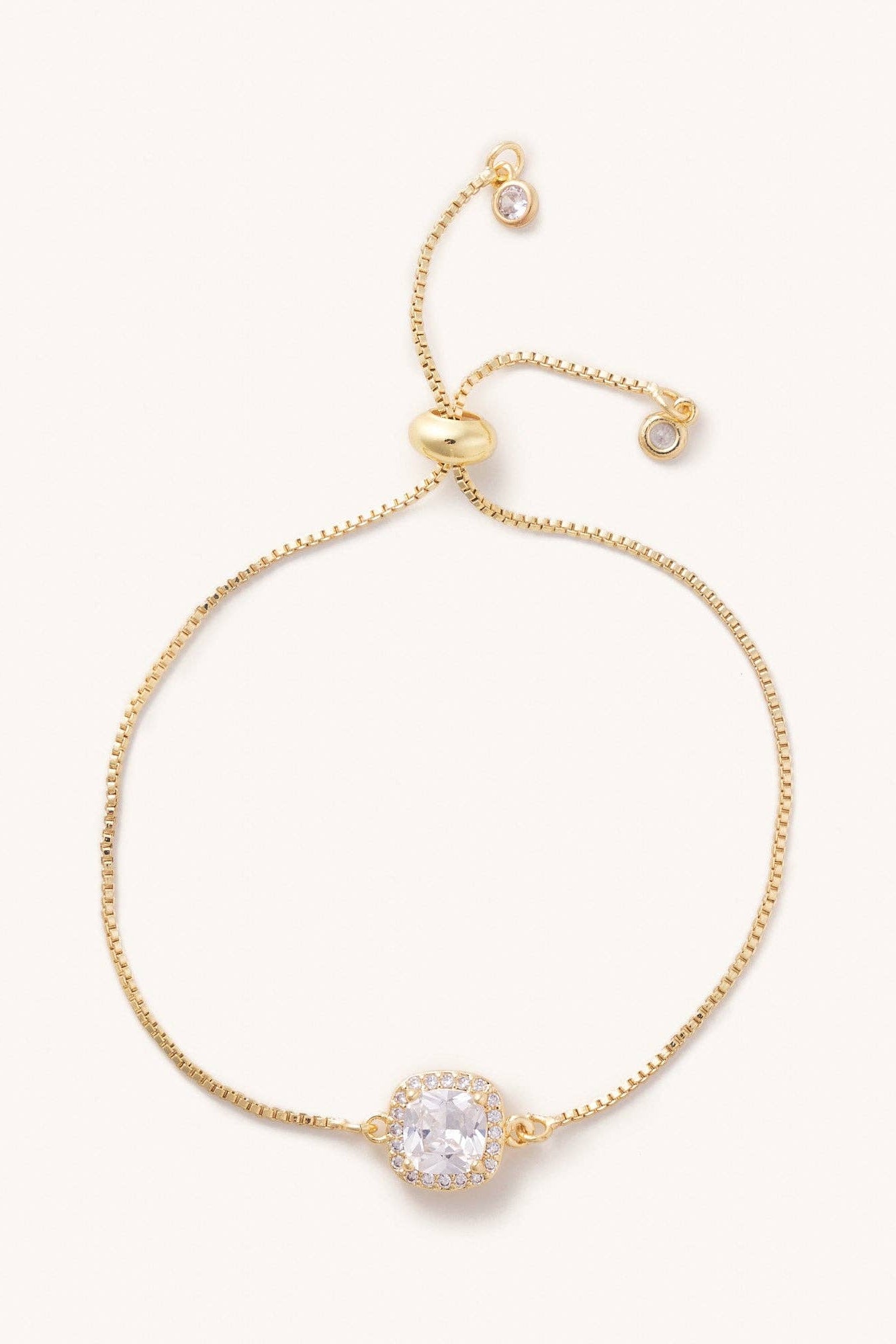 Gold bracelet with a clear gemstone on a white background
