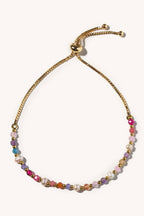 Multicolored beaded bracelet with gold chain on a white background