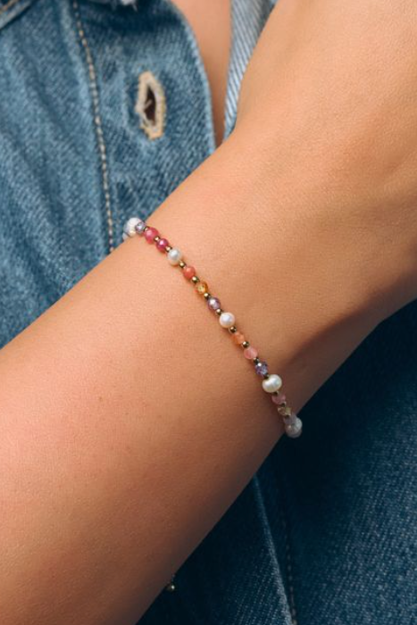 Multicolored beaded bracelet on a wrist with a denim background