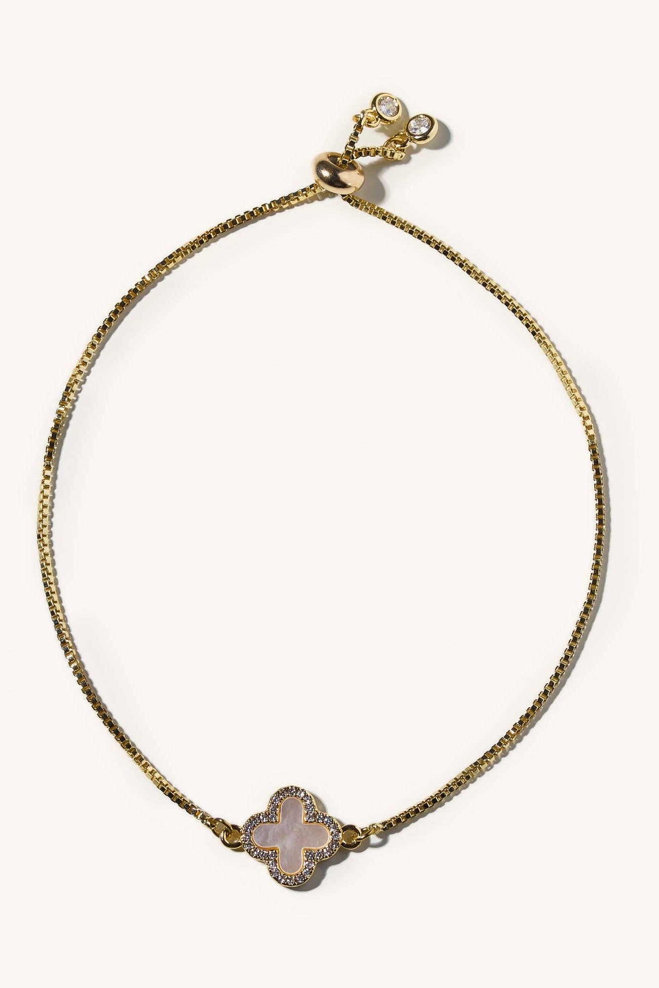 Gold bracelet with a pink stone on a white background