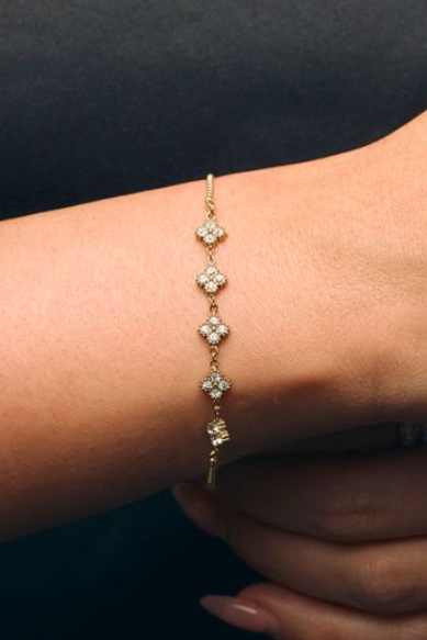 Gold bracelet with small stones on a wrist against a dark background