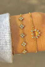 Gold bracelet with floral designs on a wrist against a blurred background