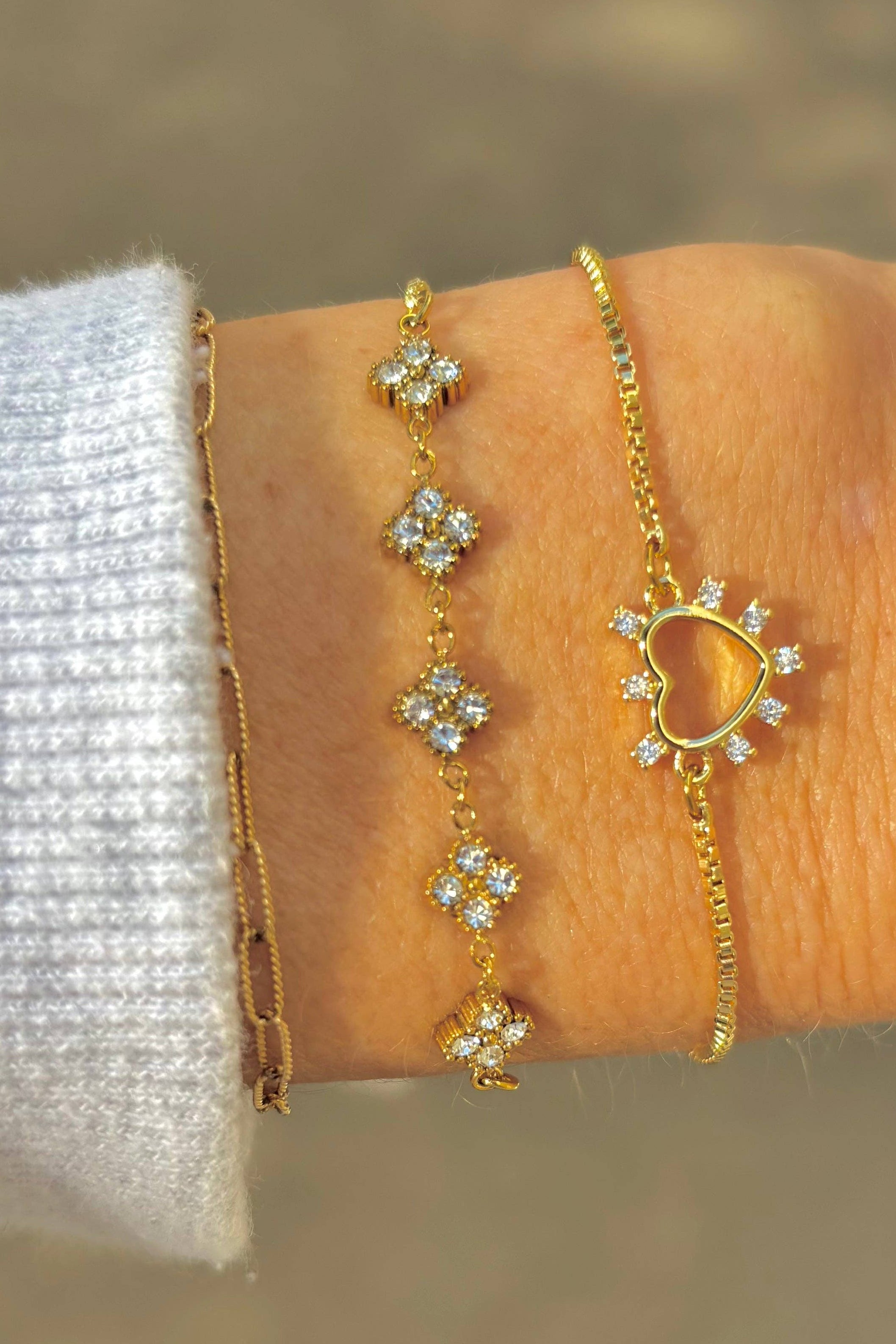 Gold bracelet with floral designs on a wrist against a blurred background