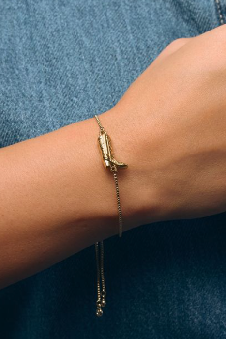 Gold bracelet on a wrist against a denim background