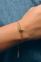 Gold bracelet on a wrist against a denim background
