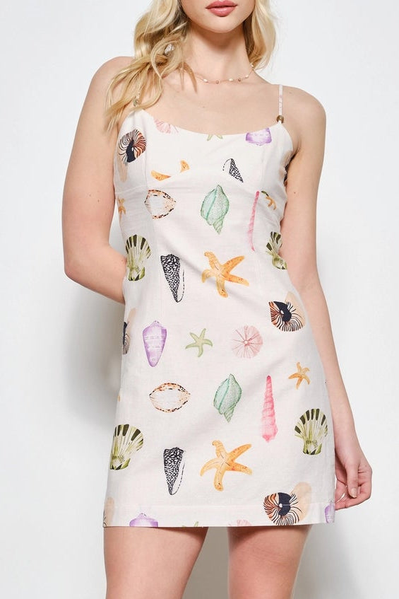 Woman wearing a sleeveless dress with shell pattern against a white background