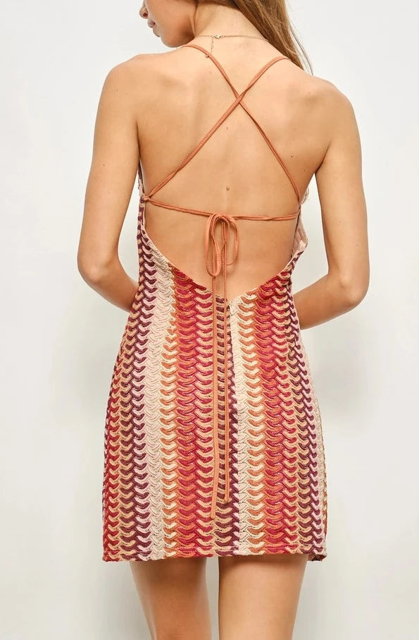 Woman wearing a patterned dress with a backless design against a plain background