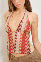 Woman wearing a colorful crochet halter top against a plain background