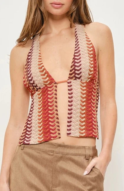 Woman wearing a patterned top and beige shorts against a white background